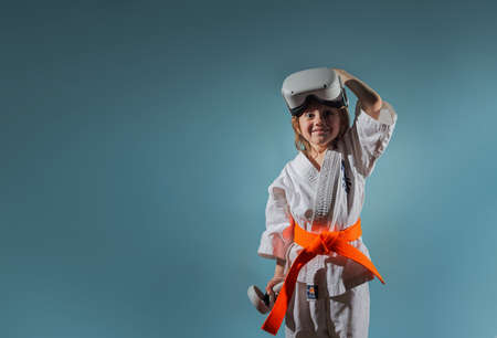 Caucasian little girl in karate uniform playing video games with VR headsetの写真素材
