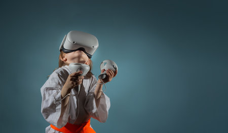 Caucasian little girl in karate uniform playing video games with VR headsetの写真素材