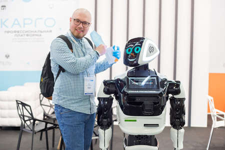Moscow, Russia - 14 April 2021: An exhibition visitor contacts an intelligent robot at one of the stands at the International exhibition of transport and logistics servicesのeditorial素材