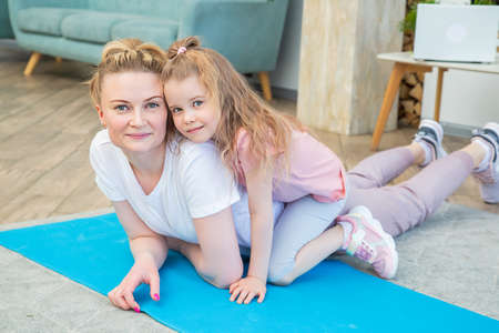Portrait of mother with daughter in sportswear huggingの写真素材
