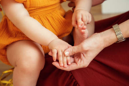 Happy Mom holds the pen of a small child in her arms close-up.