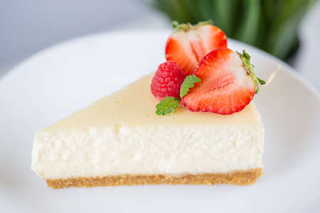 close-up of strawberry cheesecake on a white plate on a cake stand on a white backgroundの写真素材