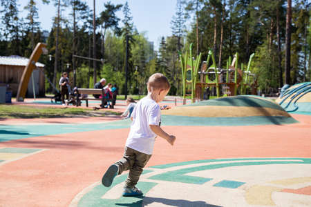 little boy walks through the territory of the playground outdoors on sunny day.