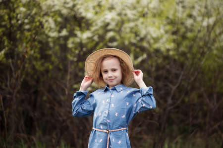 Portrait of adorable little caucasian girl 5 years old in the park standing under the cherry blossoms with selective focus and blurred backgroundの写真素材