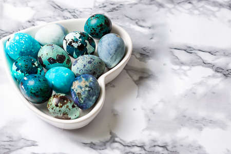 Easter blue quail eggs in a plate in the shape of a heart on a wooden table.の写真素材