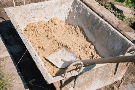 Uploading sand into a cement mixture for pouring a garden path, construction work on a garden plotの写真素材