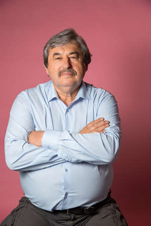Portrait of elderly man on pink color background looking at cameraの写真素材