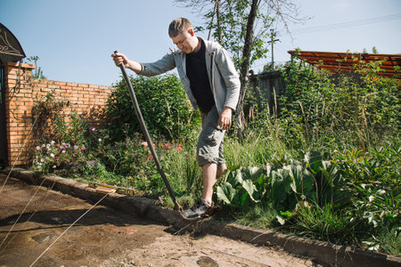 Man lays curbstone for grouting garden path, construction work on garden plotの写真素材