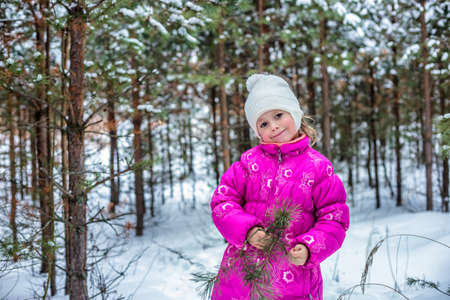 Little girl in warm clothes playing in the winter forest, spending time outdoorsの写真素材