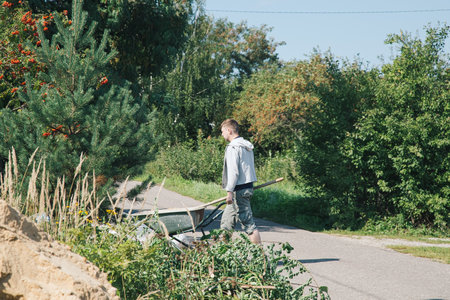 A man carries a garden wheelbarrow for loading sand to fill the pathsの写真素材