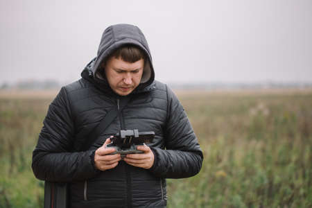 Portrait of drone operator flying aircraft quadcopter near the forest. Technology details with remote controlの写真素材