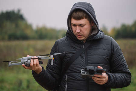 Man holding drone and remote control against field background.の写真素材