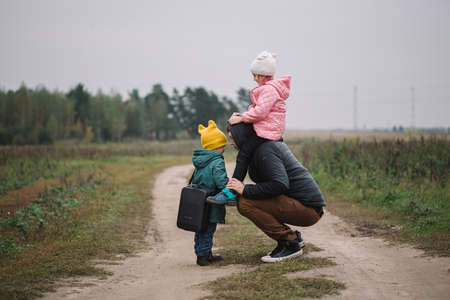 Happy family with two kids walking in the field autumn time. Dad carries his daughter on his...