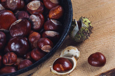 Close up view of chestnuts in a cast iron pan on a wooden background
