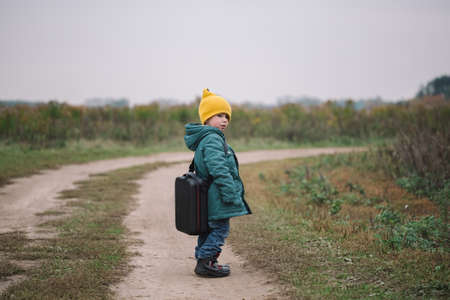 Little caucasian boy carring big case with drone in the field, side view.の写真素材