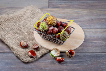 Chestnuts in a metal grocery basket on a wooden background.の写真素材