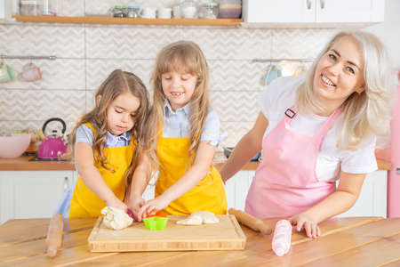 Selective focus of mother and daughters cooking together in the kitchen. Home cooking conceptの写真素材
