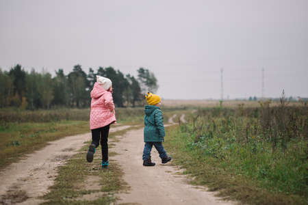 Children run into the field. Children play in the field running from flying droneの写真素材