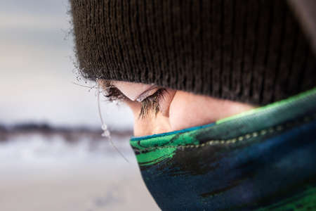 Close up view of a caucasian man facewith scarf as mask and hooded winter jacket.の写真素材