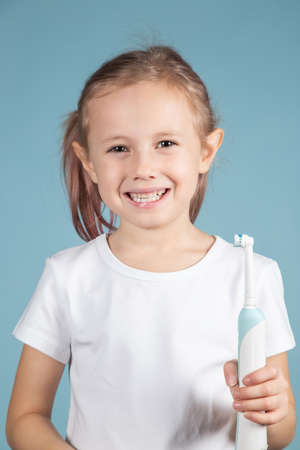 Adorable little caucasian child holding tooth brushStanding Over blue Background, hygiene concept