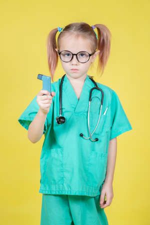 Portrait of little girl dressed in doctors green coat with an asthma inhaler