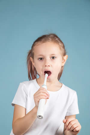 Adorable little caucasian child brushing teeth Standing Over blue Background