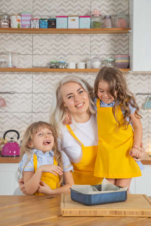 Caucasian Mom and two daughters taste the cookies just cooked together in the kitchen. Home cooking conceptの写真素材
