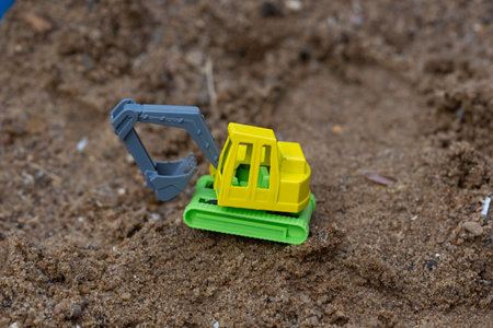 Bright colorful yellow green plastic toy truck in sandbox.の写真素材