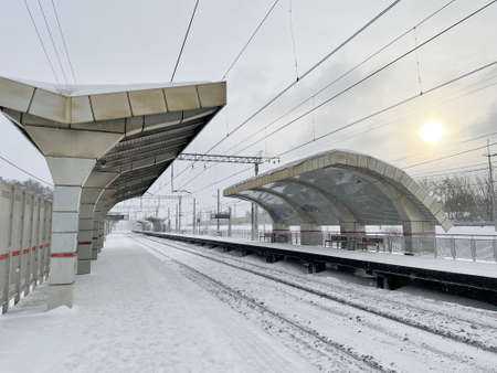 Empty railway platform without passengers in winter at the sunset. Railway, cold weather conceptの写真素材