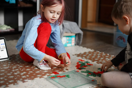Little caucasian girl playing a board game on the floor in her room,lifestyle toned photo at homeの写真素材