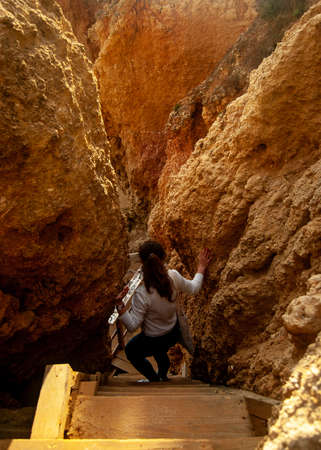 A girl wearing white is doing downstairs between giant cliffsのeditorial素材