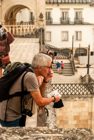 Coimbra, Portugal - August 12, 2021: A tourist with a camera is observing Paco das Escolas Square of the Coimbra University - Vertical, Coimbra, Portugal, Selective focusのeditorial素材