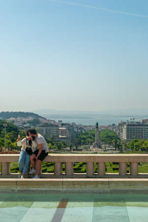Lisbon, Portugal - May 29, 2021: A couple kissing and taking a selfie against the background of the city of Lisbon - Portugal, Vertical, Selective focusのeditorial素材