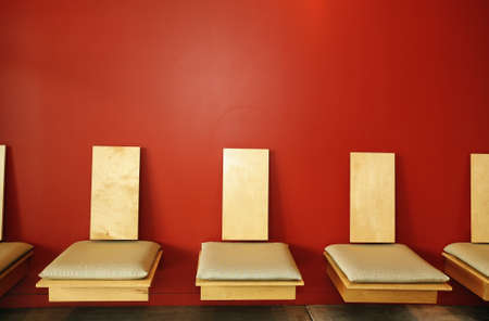 Stylish chairs in modern waiting room across red wallの写真素材
