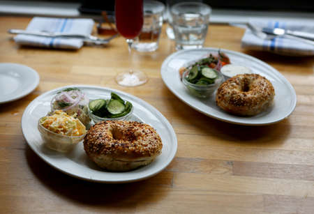 Platters with cream cheese, bagels, coleslaw, cucumber salad and white fish salad on restaurant table settingの写真素材