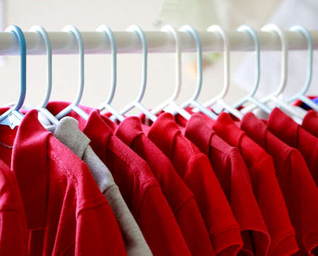 Red and one gray school uniform shirts on hangers. Selective focus.の写真素材