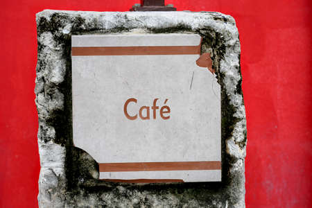 Old abandoned broken textured "cafe" sign on red backgroundの写真素材