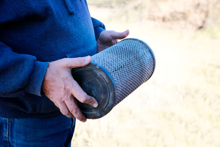 Mechanic holds large tractor dirty air filter, ready to change!の写真素材