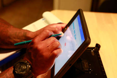 Close up of hands of African-American manager working on portable tablet. Work in progress concept.