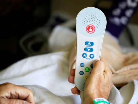 Patient holding TV remote with nurse call buttonの写真素材