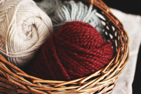 Burgundy wool yarn in wooden brown basket with needlesの写真素材