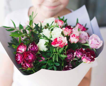 The child smiling and holding a bouquet of white and pinkの写真素材