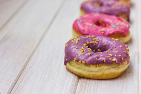 Fresh donuts with colorful glaze on the white wooden backgroundの写真素材