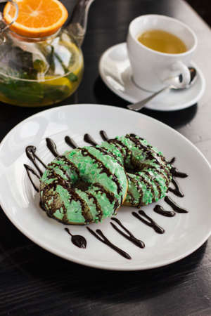 The donuts on the plate, kettle with herbal tea and on black tableの写真素材