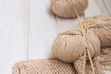 Beige Merino yarn with bamboo needles on white wooden backgroundの写真素材