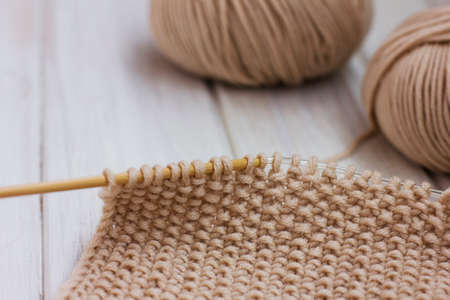 Knitting. Beige yarn on white background