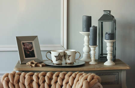Vintage sofa table with candles, knitted blanket in Scandinavian interior