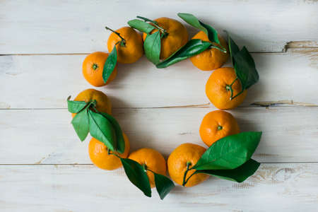 The Wreath of Fresh tangerines with Leaves on White wooden background. The view from the topの写真素材