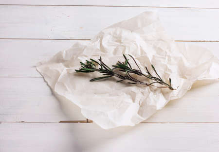 Two sprigs of rosemary on paper on white wooden backgroundの写真素材