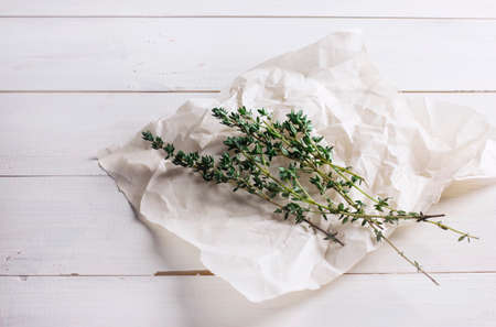 The thyme sprigs on paper on white wooden backgroundの写真素材